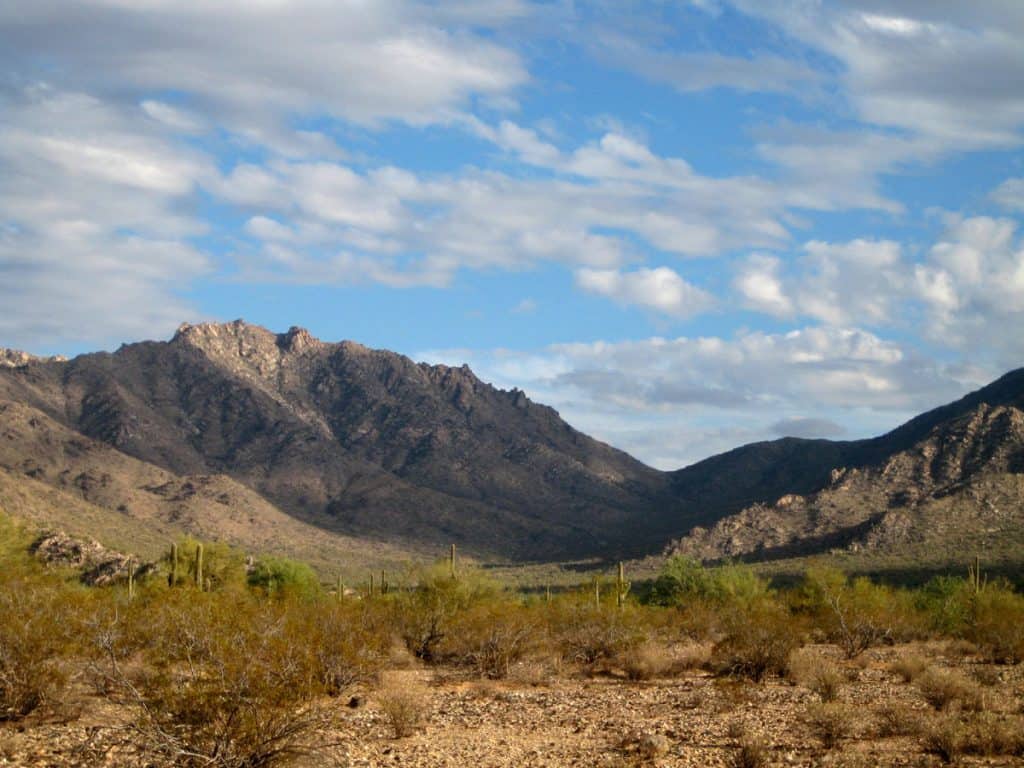 Harquahala Mountains lit by sun under a partly cloudy sky
