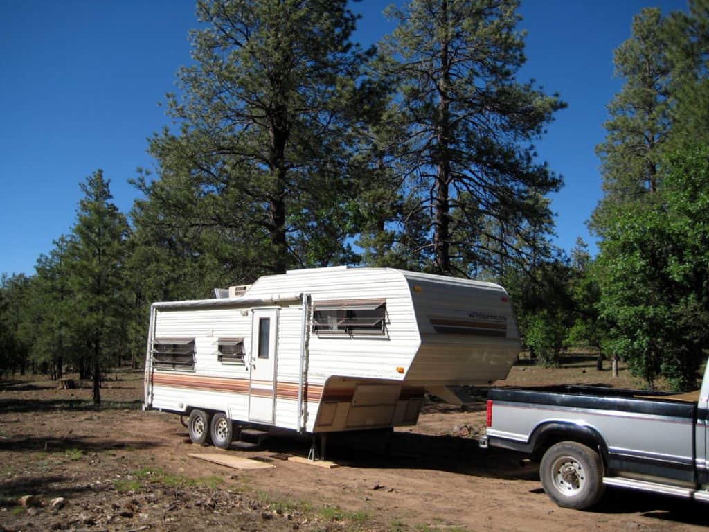 5th wheel travel trailer camped below tall pines