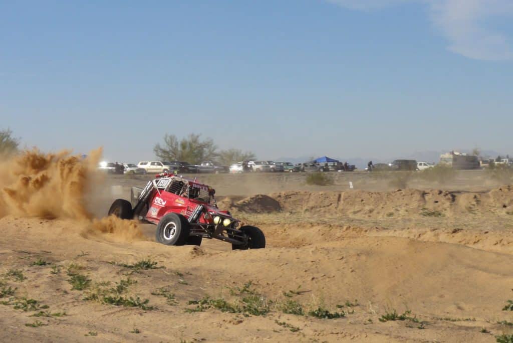 Racing buggy kicking up sand on the race course