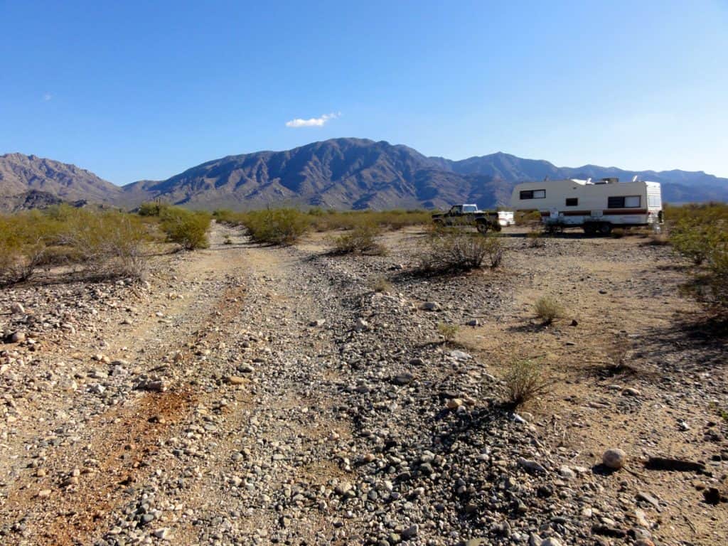 Truck and 5th wheel travel trailer camped in desert below the mountains